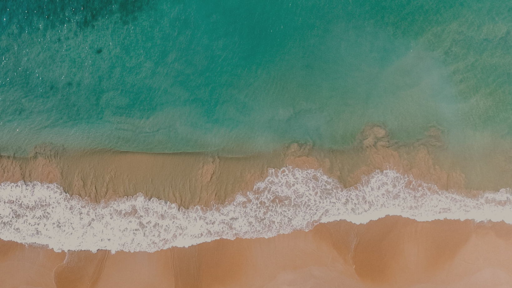Aerial drone shot — turquoise sea meeting golden beach